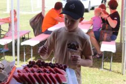 Na zdjęciu widzimy chłopca, który korzysta z poczęstunku przygotowanego przez mieszkańców Okuninki na Piknik Rodzinny.