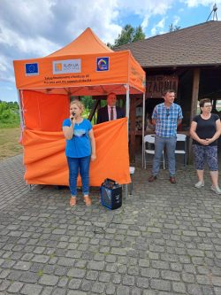 Na zdjęciu widzimy pomarańczowy namiot Gminy Włodawa oraz pracowników urzędu. Pod namiotem stoi Wójt Gminy Włodawa, Dariusz Semeniuk.