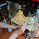 Na zdjęciu widzimy członkinię KGW w Sobiborze nakładającą popcorn z maszyny podczas Dnia Rodziny w Sobiborze.