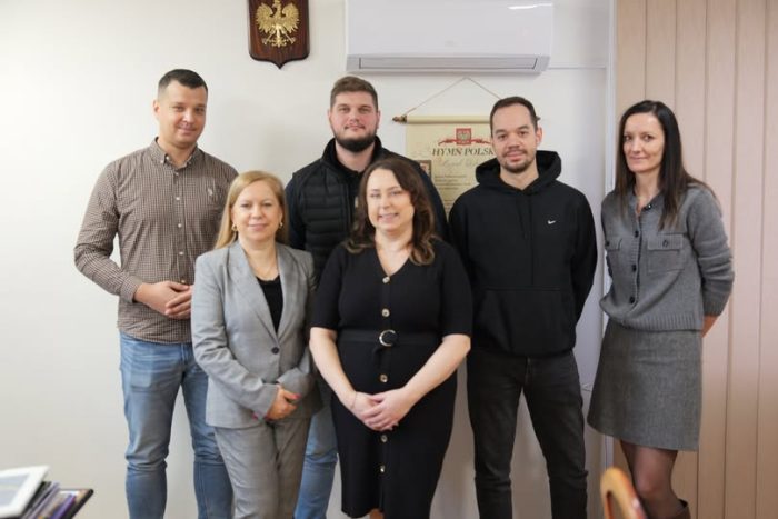 Na zdjęciu grupa osób pozująca do zdjęcia w gabinecie na tle godła Polski